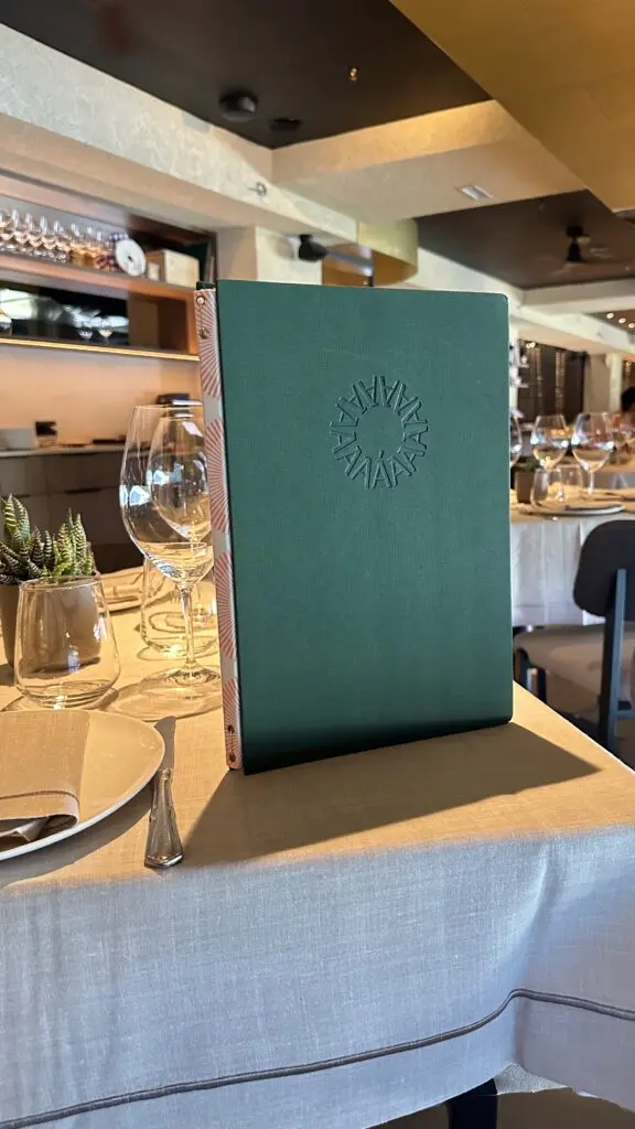 Carta personalizada verde con el logotipo estampado, sobre una mesa de restaurante