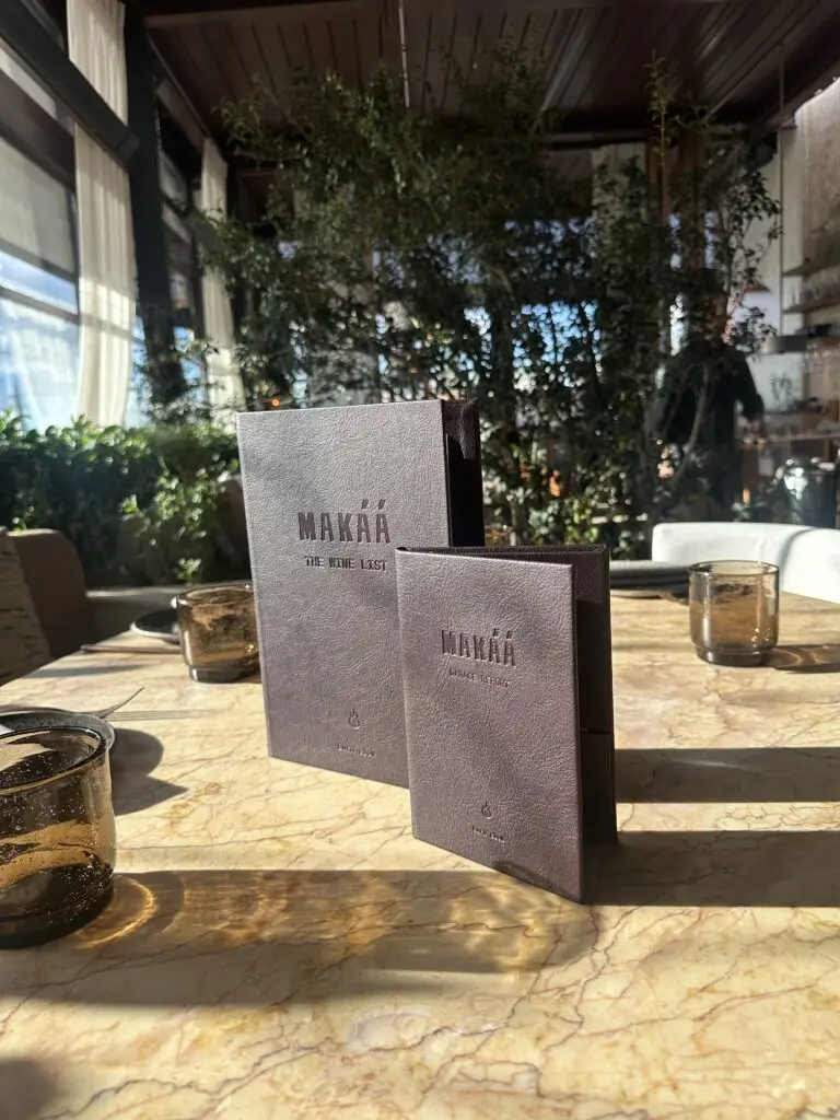 Dos cartas personalizadas color berenjena con el logotipo del restaurante sobre una mesa de mármol
